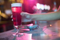 Mujer sosteniendo vaso de cóctel rosa en el bar - foto de stock