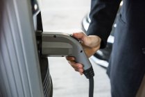 Крупный план зарядного автомобиля человека на электрозарядной станции — стоковое фото