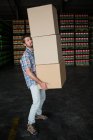 Side view of man carrying cardboard boxes in warehouse — Stock Photo