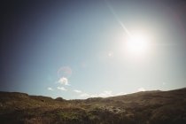 Красивый вид на холм под ярким солнечным светом в голубом небе — стоковое фото