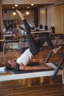 Woman practicing pilates on reformer in fitness studio — Stock Photo