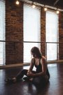Танцовщица сидит на полу и использует мобильный телефон в танцевальной студии — стоковое фото