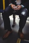 Baixa seção de homem de negócios usando telefone celular enquanto viaja em ônibus — Fotografia de Stock