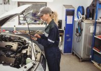Female mechanic using digital tablet in repair shop — Stock Photo