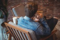 Вид сзади на человека разговаривающего по мобильному телефону в кафе — стоковое фото