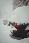 Автомобили, покрытые снегом, на парковке зимой — стоковое фото