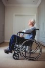 Thoughtful senior man sitting on wheelchair at home — Stock Photo