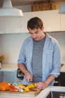 Мужчина режет овощи на кухне дома — стоковое фото