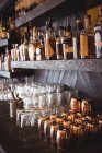 Gros plan des bouteilles et des verres disposés sur les étagères d'un bar — Photo de stock