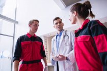 Doctor talking to paramedic in corridor at hospital — Stock Photo