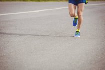 Low section of athlete running on the road — Stock Photo