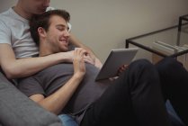 Lächelndes homosexuelles Paar nutzt gemeinsam digitales Tablet zu Hause — Stockfoto