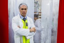 Retrato del técnico de pie con los brazos cruzados en la fábrica de carne - foto de stock