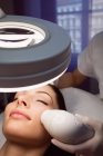 Dermatólogo dando masaje facial al paciente a través de levantamiento sónico en clínica - foto de stock