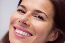Retrato de cerca de una mujer adulta sonriendo y mirando a la cámara - foto de stock
