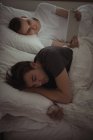 Гей-пара використовуючи мобільний телефон і цифровий планшетний лежачи на ліжку в спальні — стокове фото