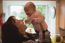 Mother playing with smiling baby in kitchen at home — Stock Photo
