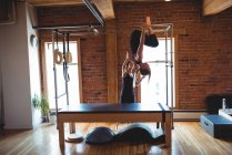 Entraîneur aidant femme tout en pratiquant pilates sur l'équipement d'exercice dans le studio de fitness — Photo de stock