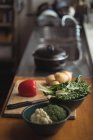 Pommes de terre, oignon, laitue avec brocoli sur planche à découper dans le plan de travail de la cuisine — Photo de stock