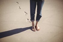 Seção baixa de uma mulher andando na praia de areia — Fotografia de Stock