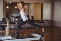 Женщина практикует пилатес на реформаторе в фитнес-студии — стоковое фото