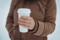 Середина жінки в теплій куртці, що тримає чашку кави взимку — стокове фото