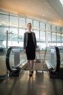 Geschäftsfrau nahe Rolltreppe mit Gepäck am Flughafen — Stockfoto