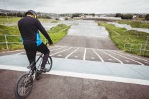 Ciclista in piedi con BMX bike sulla rampa di partenza allo skatepark — Foto stock