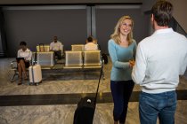 Happy couple holding hands while standing in waiting area at airport terminal — Stock Photo