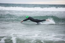 Athlete in wet suit swimming in sea water — Stock Photo