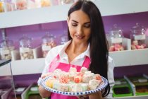 Жінка-магазин тримає лоток турецьких солодощів за лічильником в магазині — стокове фото