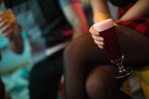Mujer sosteniendo un vaso de bebida en el bar - foto de stock