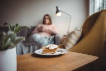 Тарілка випічки на дерев'яному столі з жінкою на фоні у вітальні вдома — стокове фото