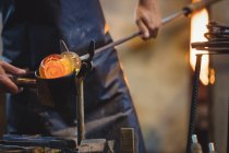 Close-up of glassblower forming and shaping a molten glass at glassblowing factory — Stock Photo