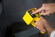 Mani tagliate di lavoratori maschi che utilizzano uno strumento giallo in fabbrica — Foto stock