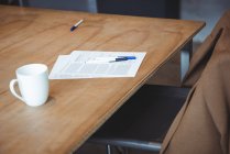 Xícara de café e documento com canetas na mesa no escritório — Fotografia de Stock