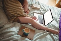 Женщина с ноутбуком на кровати дома — стоковое фото