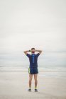 Atleta in piedi con le mani dietro la testa sulla spiaggia — Foto stock