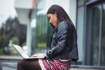 Жінка використовує ноутбук за межами офісної будівлі — стокове фото