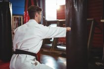Karatê jogador perfurando saco de boxe no estúdio de fitness — Fotografia de Stock
