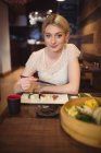 Portrait of smiling woman eating sushi in restaurant — Stock Photo