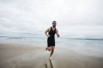 Uomo in costume da bagno e cuffia in spiaggia — Foto stock