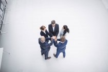 Overhead view of business people stacking hands together in office — Stock Photo