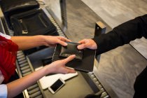 Primer plano del personal femenino que entrega la cartera y los productos lácteos al pasajero en la terminal del aeropuerto - foto de stock