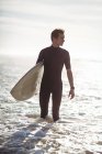 Продуманий серфер, що стоїть з дошкою для серфінгу в морі — стокове фото