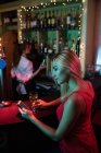 Frau benutzt Handy, während sie ein Glas Wein am Tresen in der Bar trinkt — Stockfoto