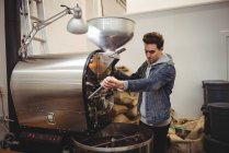 Man using coffee grinding machine in coffee shop — Stock Photo