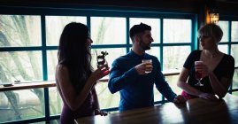 Three friends enjoying drinks in bar interior — Stock Photo