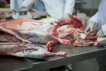 Açougueiros limpando carne na fábrica de carne — Fotografia de Stock