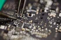 Close-up de microchip sendo fixado na placa de circuito usando ferro de solda — Fotografia de Stock
